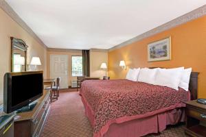 a hotel room with a bed and a flat screen tv at Sunset Inn Daytona Beach in Daytona Beach