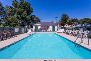 a swimming pool with chairs and a house at Days Inn by Wyndham Simpsonville in Simpsonville