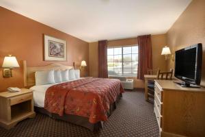 a hotel room with a bed and a flat screen tv at Days Inn & Suites by Wyndham Surprise in Surprise