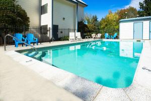 a swimming pool with blue chairs and a house at Days Inn by Wyndham Corvallis in Corvallis