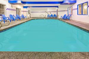 a swimming pool with blue chairs and chairs at Days Inn & Suites by Wyndham Gresham in Gresham