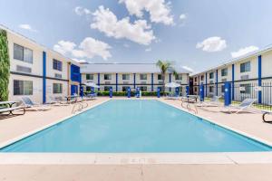 une piscine avec des chaises et un bâtiment dans l'établissement Days Inn & Suites by Wyndham Laredo, à Laredo