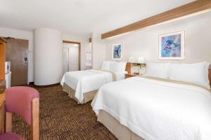 ein Hotelzimmer mit 2 weißen Betten und einer Küche in der Unterkunft Days Inn by Wyndham Liberal KS in Liberal