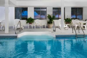 una piscina con sillas blancas, mesa y sillas en Days Inn by Wyndham Liberal KS, en Liberal