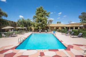 a swimming pool in a courtyard with chairs and a building at Days Hotel by Wyndham Peoria Glendale Area in Peoria