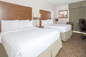 a hotel room with two beds and a chair at The Grand Inn Peoria in Peoria