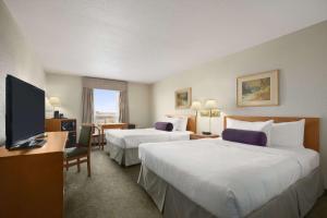 a hotel room with two beds and a flat screen tv at Days Inn by Wyndham Red Deer in Red Deer