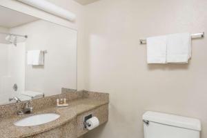a bathroom with a sink and a toilet and a mirror at The Grand Inn Peoria in Peoria