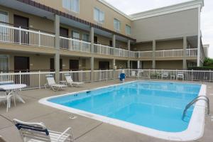 a pool in front of a building with chairs and a table at Days Inn by Wyndham Florence Cincinnati Area in Florence