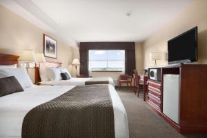 a hotel room with two beds and a flat screen tv at Days Inn & Suites by Wyndham Langley in Langley