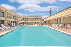 a swimming pool at a hotel with chairs and a building at Days Inn by Wyndham Attalla in Attalla