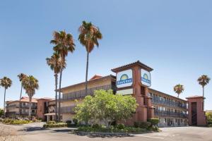 a hotel with a clock tower in front of a building at Days Inn by Wyndham San Jose Airport in Milpitas