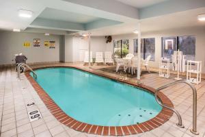 a pool in a hotel room with chairs and tables at Days Inn by Wyndham Blue Springs in Blue Springs