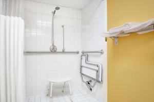 a bathroom with a shower with a stool in it at Days Inn by Wyndham Burlington East in Haw River