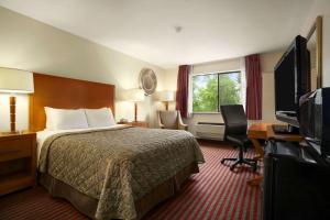 a hotel room with a bed and a flat screen tv at Days Inn by Wyndham Kent 84th Ave in Kent