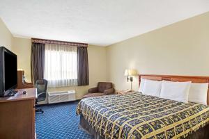 a hotel room with a bed and a flat screen tv at Days Inn by Wyndham Brigham City in Brigham City