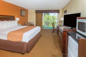 a hotel room with a bed and a desk with a television at Days Inn by Wyndham Palm Springs in Palm Springs