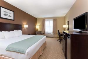 a hotel room with a large bed and a flat screen tv at Palm Coast Hotel & Suites-I-95 in Palm Coast