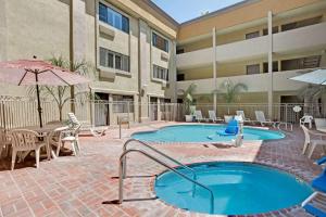 a pool with a table and chairs and a building at Days Inn by Wyndham West Covina in West Covina