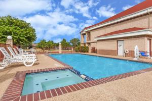 a swimming pool in front of a building with a house at Days Inn by Wyndham Granbury in Granbury