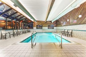 a swimming pool in a building with tables and chairs at Days Inn & Suites by Wyndham Logan in Logan