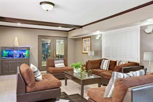 a living room with brown furniture and a flat screen tv at Days Inn by Wyndham West Covina in West Covina