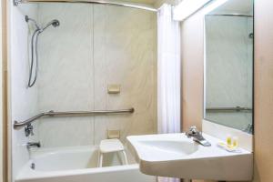 W łazience znajduje się umywalka, wanna i lustro. w obiekcie Days Inn & Suites by Wyndham Logan w mieście Logan