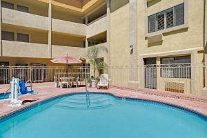 a swimming pool with an umbrella and a table and chairs at Days Inn by Wyndham West Covina in West Covina