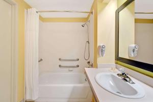 a bathroom with a sink and a tub and a shower at Days Inn & Suites by Wyndham DeSoto in DeSoto