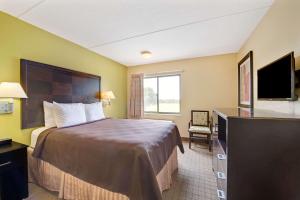 a hotel room with a bed and a flat screen tv at Days Inn & Suites by Wyndham DeSoto in DeSoto