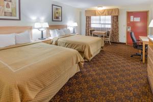 Habitación de hotel con 2 camas y escritorio en Days Inn by Wyndham Black Bear en Salem