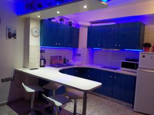 a large kitchen with a white counter and blue lighting at Cosy apartment Acropolis Point-3 in Athens