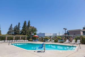 a swimming pool with chairs and an umbrella at Days Inn & Suites by Wyndham Sunnyvale in Sunnyvale