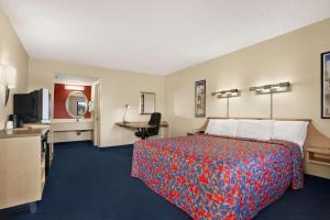 a hotel room with a bed and a desk at Days Inn by Wyndham Buena Park in Buena Park