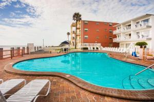 a swimming pool at a resort with chairs and condos at Arya Blu Inn and Suites in Ormond Beach