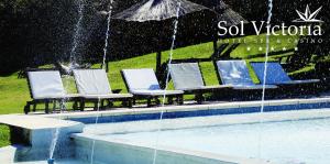 a pool with chairs and an umbrella in the rain at Sol Victoria Hotel SPA & Casino in Victoria