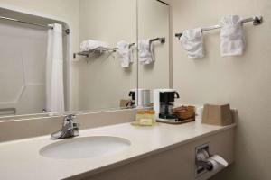 a bathroom with a sink and a mirror at Days Inn & Suites by Wyndham Romeoville in Romeoville +13 photos