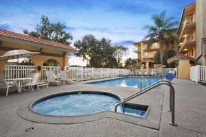 a pool in a courtyard with chairs and a building at Days Inn by Wyndham Buena Park in Buena Park