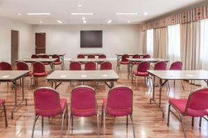 a conference room with tables and red chairs at Days Inn & Suites by Wyndham Sunnyvale in Sunnyvale