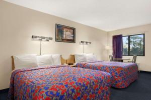 a hotel room with two beds and a window at Days Inn by Wyndham Buena Park in Buena Park