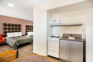 a kitchen with a sink and a room with a bed at Arya Blu Inn and Suites in Ormond Beach