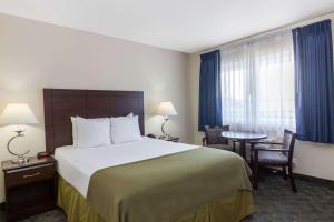 a hotel room with a large bed and a table at Days Inn by Wyndham Santa Maria in Santa Maria