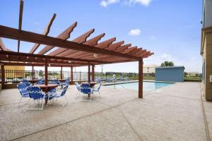 un patio con mesas y sillas y una piscina en Days Inn & Suites by Wyndham Galveston West/Seawall en Galveston