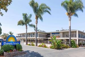a building with palm trees in front of it at Days Inn by Wyndham Santa Maria in Santa Maria