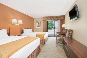 a hotel room with two beds and a flat screen tv at Days Inn & Suites by Wyndham Red Rock-Gallup in Gallup