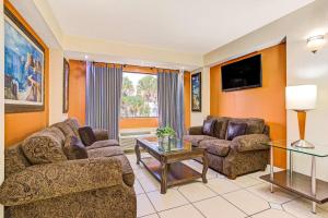a living room with two couches and a tv at Days Inn & Suites by Wyndham Tampa - Ybor City in Tampa +16 photos