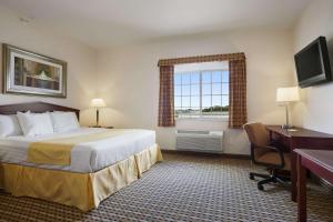 a hotel room with a bed and a desk and a window at Days Inn & Suites by Wyndham Columbus NE in Columbus +65 photos