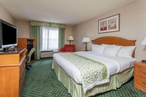 a hotel room with a large bed and a flat screen tv at Days Inn & Suites by Wyndham Warren in Warren
