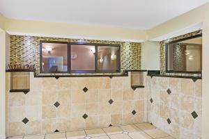 a bathroom with two mirrors and a tiled wall at Days Inn & Suites by Wyndham Tampa - Ybor City in Tampa