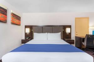 1 dormitorio con 1 cama grande con manta azul en Days Inn by Wyndham Woodbury Long Island en Woodbury